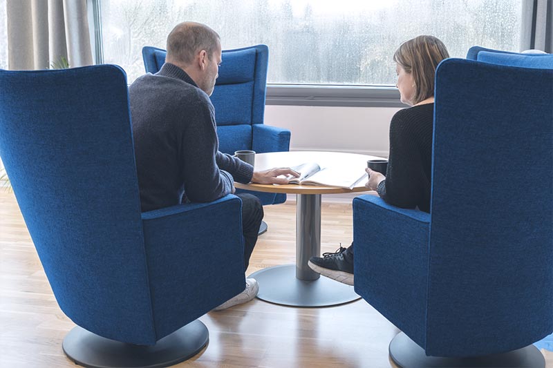 To personer som sitter i hver sin stol og snakker sammen